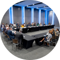 Meeting room with people seated around a U-shaped table